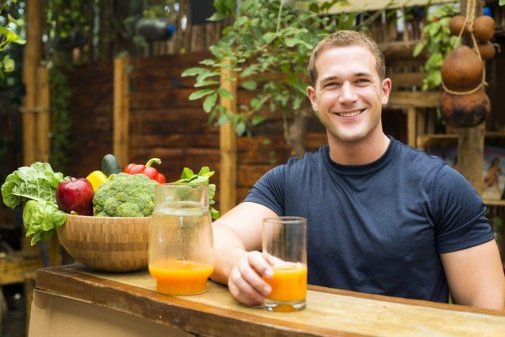 Young fitted man enjoying an organic juice and vegetable in a ra