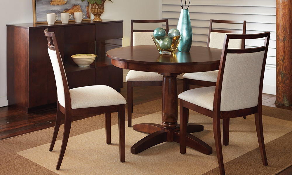 Round wood dining table and cream upholstered and wooden chairs.