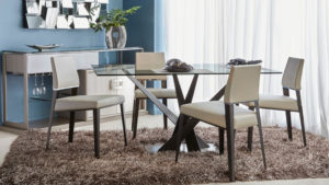 Rectangular glass top dining table with metal base and beige dining chairs.