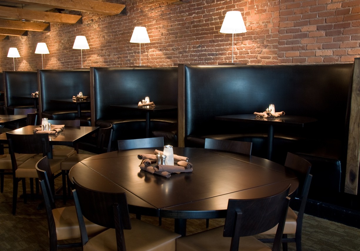 A modern restaurant with high-backed booths and sleek tables in black.