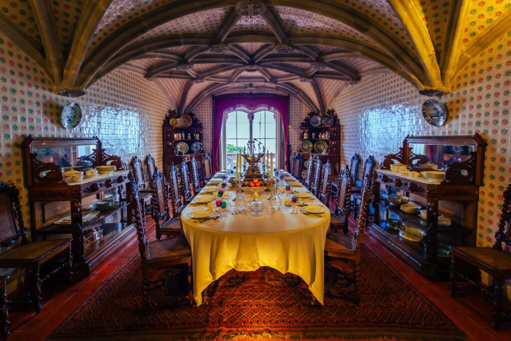 A dining room during the Renaissance period with a long table formally set and ornate dining furniture.