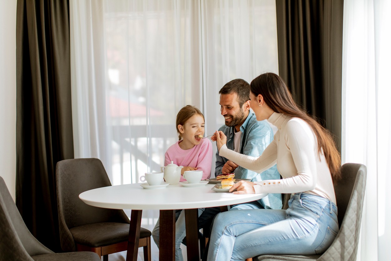 A family eats at a dinette set in a small dining nook at home.