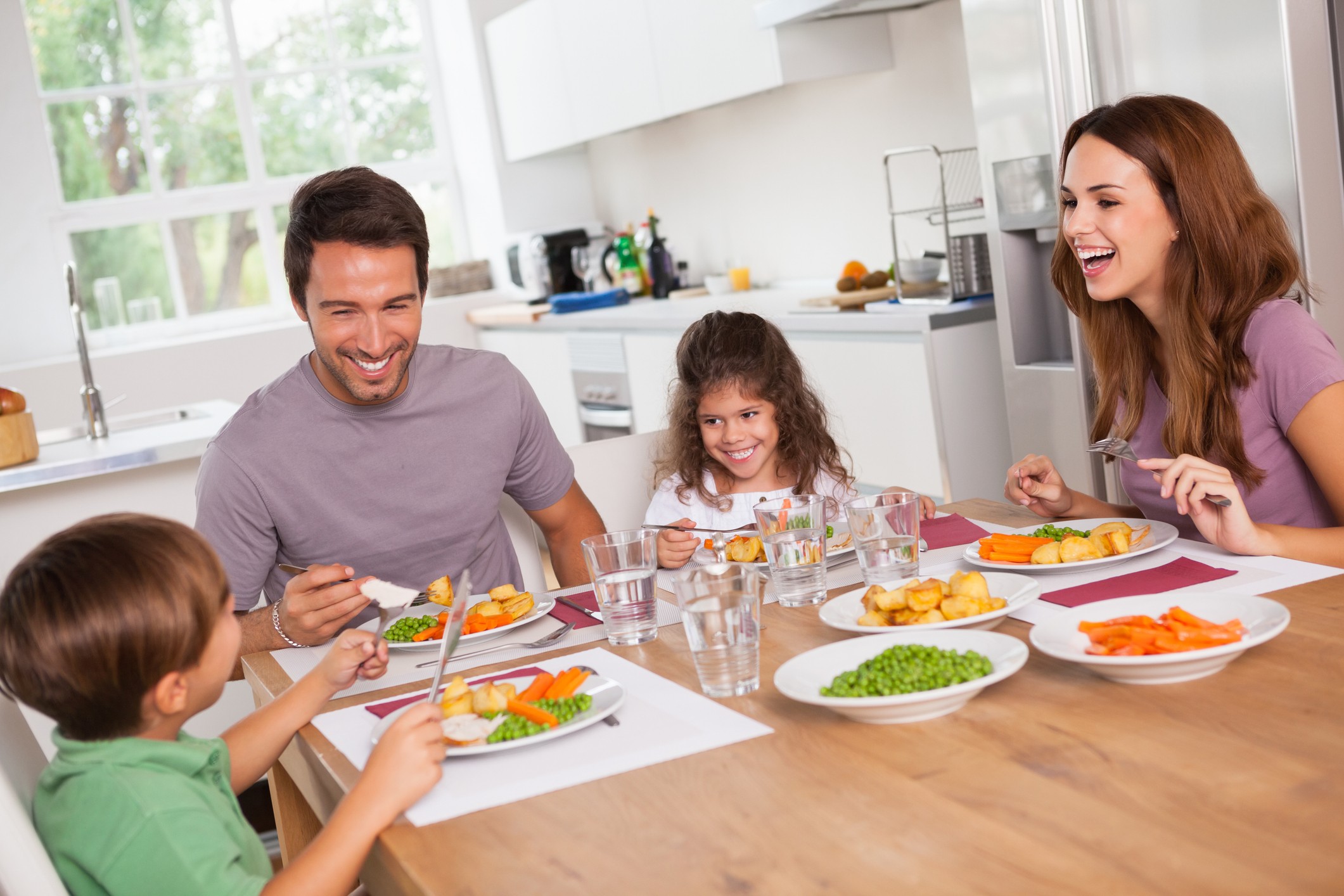 A family eats dinner together at their kitchen table.