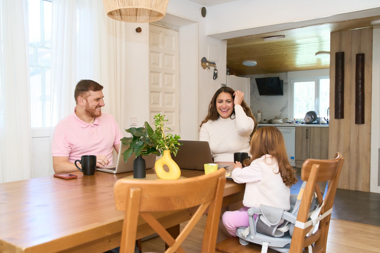 family eating dinner together and laughing on dining chairs.